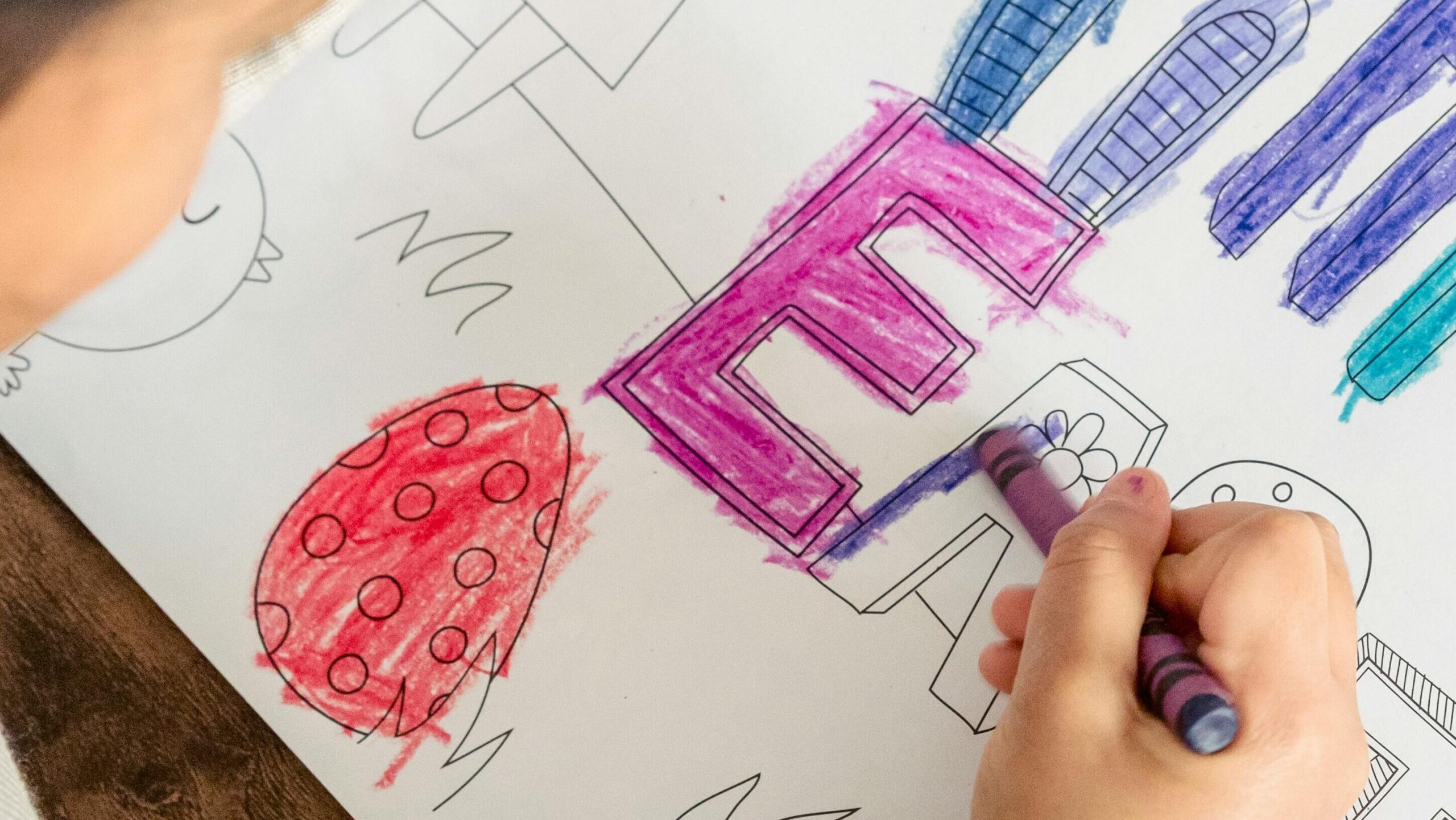 A child creatively colors an Easter-themed drawing using crayons, showcasing holiday celebration.