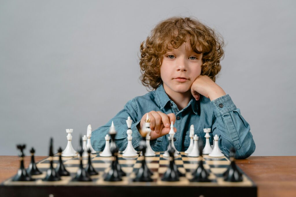 A thoughtful child playing chess, focusing on strategic moves with a serious expression.